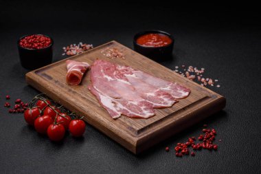 Lezzetli füme jamon dilimleri ya da koyu beton arka planda tuzlu, baharatlı ve otlu jambon.