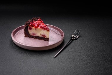 Koyu beton arka planda seramik tabakta kirazlı güzel bir dilim cheesecake.