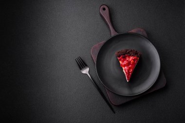 Koyu beton arka planda seramik tabakta kirazlı güzel bir dilim cheesecake.