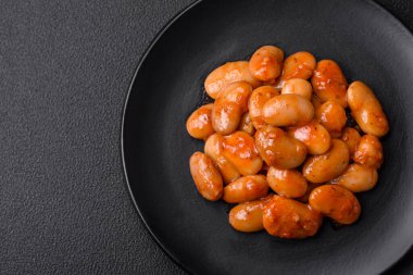 Beyaz bir seramik kasede, koyu beton bir arka planda domatesin içindeki lezzetli konserve fasulyeler.