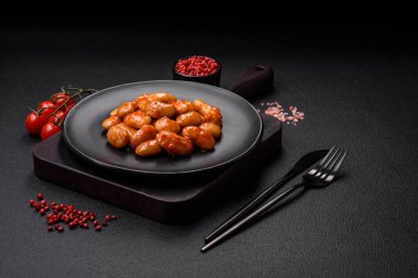 Beyaz bir seramik kasede, koyu beton bir arka planda domatesin içindeki lezzetli konserve fasulyeler.