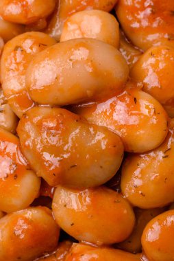 Beyaz bir seramik kasede, koyu beton bir arka planda domatesin içindeki lezzetli konserve fasulyeler.