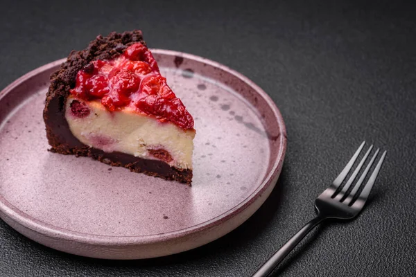 Koyu beton arka planda seramik tabakta kirazlı güzel bir dilim cheesecake.