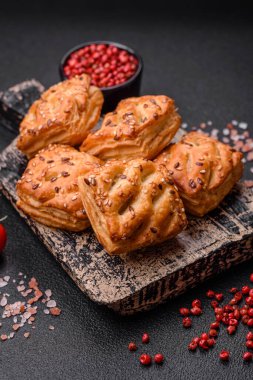 Sosisli çıtır çıtır mini puflar ya da koyu beton arka planda tuzlu et, kekik ve susam.