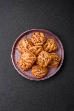 Sosisli çıtır çıtır mini puflar ya da koyu beton arka planda tuzlu et, kekik ve susam.