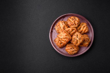 Sosisli çıtır çıtır mini puflar ya da koyu beton arka planda tuzlu et, kekik ve susam.