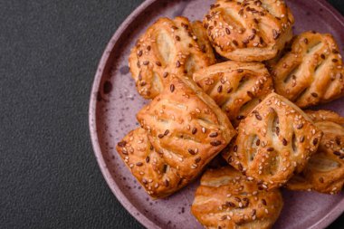 Sosisli çıtır çıtır mini puflar ya da koyu beton arka planda tuzlu et, kekik ve susam.