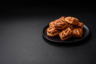 Sosisli çıtır çıtır mini puflar ya da koyu beton arka planda tuzlu et, kekik ve susam.