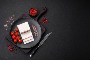 Lezzetli taze ricotta peyniri. Koyu beton arka planda sebze, tuz ve baharatla dilimlenmiş.