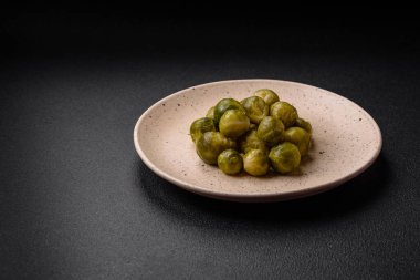 Lezzetli kaynamış Brüksel lahanaları, koyu beton arka planda seramik bir tabakta. Vejetaryen yemeği.