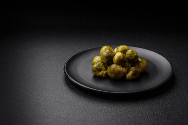 Lezzetli kaynamış Brüksel lahanaları, koyu beton arka planda seramik bir tabakta. Vejetaryen yemeği.