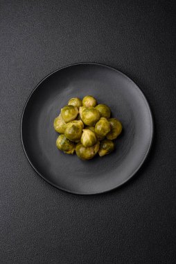 Lezzetli kaynamış Brüksel lahanaları, koyu beton arka planda seramik bir tabakta. Vejetaryen yemeği.