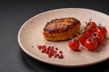 Lezzetli taze kızarmış vejetaryen soya pirzolası, tuzlu, baharatlı ve sebzeli, koyu beton bir zeminde seramik bir tabakta.
