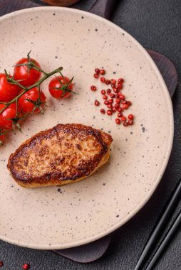 Lezzetli taze kızarmış vejetaryen soya pirzolası, tuzlu, baharatlı ve sebzeli, koyu beton bir zeminde seramik bir tabakta.