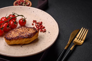 Lezzetli taze kızarmış vejetaryen soya pirzolası, tuzlu, baharatlı ve sebzeli, koyu beton bir zeminde seramik bir tabakta.