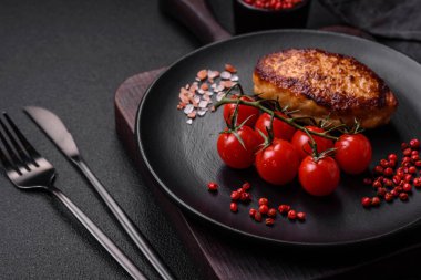 Lezzetli taze kızarmış vejetaryen soya pirzolası, tuzlu, baharatlı ve sebzeli, koyu beton bir zeminde seramik bir tabakta.