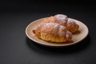 Koyu beton arka planda seramik tabakta çikolata kremalı lezzetli çıtır kruvasanlar.