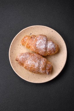 Koyu beton arka planda seramik tabakta çikolata kremalı lezzetli çıtır kruvasanlar.