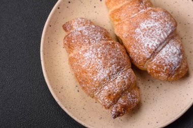 Koyu beton arka planda seramik tabakta çikolata kremalı lezzetli çıtır kruvasanlar.
