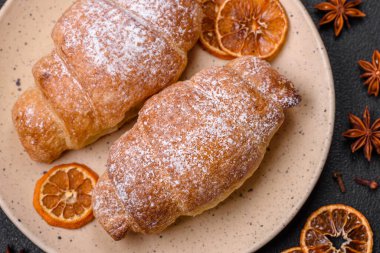 Koyu beton arka planda seramik tabakta çikolata kremalı lezzetli çıtır kruvasanlar.