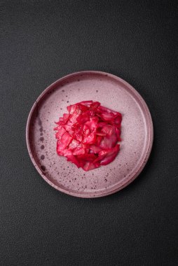 Kore usulü dilimlenmiş ve koyu beton arka planda seramik bir tabakta pişirilmiş lezzetli pembe lahana.