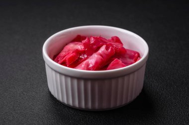 Kore usulü dilimlenmiş ve koyu beton arka planda seramik bir tabakta pişirilmiş lezzetli pembe lahana.