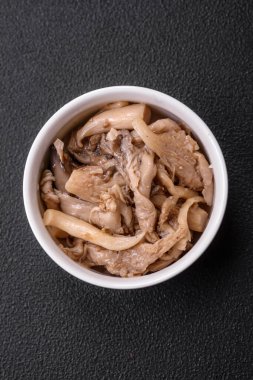 Kore usulü dilimlenmiş ve pişirilmiş lezzetli baharatlı mantarlar koyu beton arka planda seramik bir tabakta.