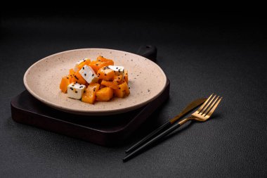 Lezzetli sulu salata dilimlenmiş kabak peyniriyle, baharatla ve susam tohumuyla seramik tabakta.