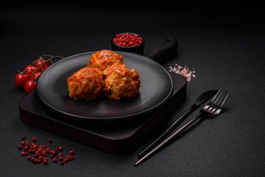 Lezzetli taze köfteler kıyma ya da domates soslu balık, havuç, soğan, tuz ve baharatlar koyu beton arka planda.