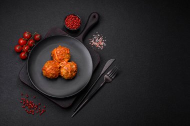 Lezzetli taze köfteler kıyma ya da domates soslu balık, havuç, soğan, tuz ve baharatlar koyu beton arka planda.