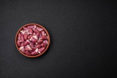 Taze çiğ tavuk, hindi ya da ördek kalbi seramik tabakta tuzlu ve baharatlı koyu beton arka planda.