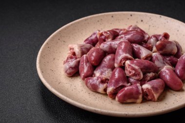 Taze çiğ tavuk, hindi ya da ördek kalbi seramik tabakta tuzlu ve baharatlı koyu beton arka planda.