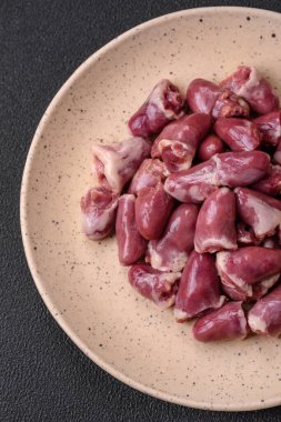 Taze çiğ tavuk, hindi ya da ördek kalbi seramik tabakta tuzlu ve baharatlı koyu beton arka planda.