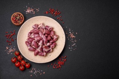 Taze çiğ tavuk, hindi ya da ördek kalbi seramik tabakta tuzlu ve baharatlı koyu beton arka planda.