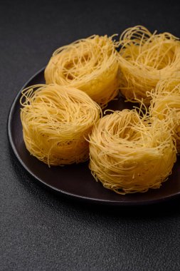 Çiğ capellini makarna ya da koyu beton arka planda tuzlu ve baharatlı erişte.
