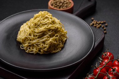 Kapellini makarna ya da pesto soslu erişte, tuz ve baharatlar koyu beton arka planda.