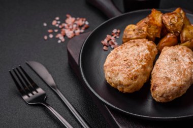 Lezzetli taze tavuk pirzolası ya da koyu beton arka planda tuz, baharat ve otlu köfte.