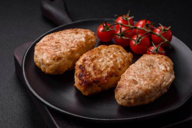 Lezzetli taze tavuk pirzolası ya da koyu beton arka planda tuz, baharat ve otlu köfte.