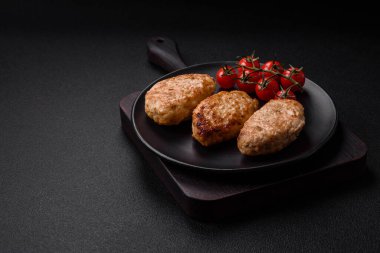 Lezzetli taze tavuk pirzolası ya da koyu beton arka planda tuz, baharat ve otlu köfte.