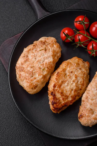 Delicious fresh chicken cutlets or meatballs with salt, spices and herbs on a dark concrete background