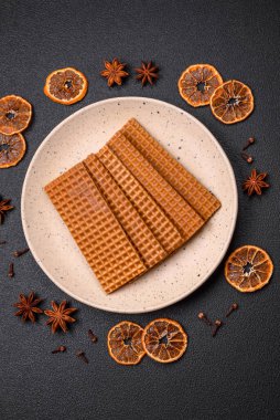 Lezzetli, çıtır çıtır, dikdörtgen waffle 'lar seramik tabakta, koyu beton arka planda.