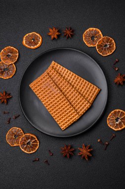 Lezzetli, çıtır çıtır, dikdörtgen waffle 'lar seramik tabakta, koyu beton arka planda.