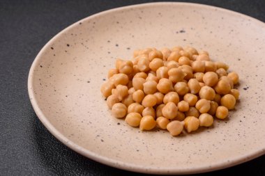 Koyu beton bir zeminde seramik tabakta lezzetli konserve nohutlar. Vejetaryen yemekleri için gerekenler