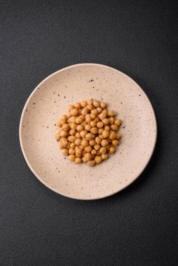 Koyu beton bir zeminde seramik tabakta lezzetli konserve nohutlar. Vejetaryen yemekleri için gerekenler