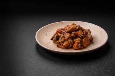 Lezzetli sebze güveci, patates, sığır eti, mantar, havuç, tuz, baharat ve otlar koyu beton arka planda.