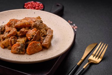 Lezzetli sebze güveci, patates, sığır eti, mantar, havuç, tuz, baharat ve otlar koyu beton arka planda.