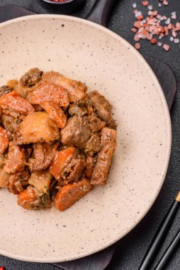 Lezzetli sebze güveci, patates, sığır eti, mantar, havuç, tuz, baharat ve otlar koyu beton arka planda.