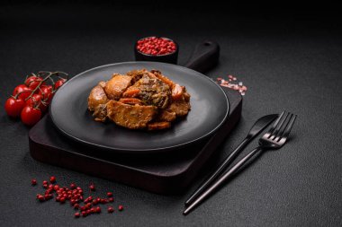 Lezzetli sebze güveci, patates, sığır eti, mantar, havuç, tuz, baharat ve otlar koyu beton arka planda.