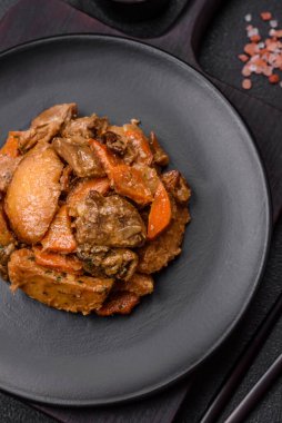 Lezzetli sebze güveci, patates, sığır eti, mantar, havuç, tuz, baharat ve otlar koyu beton arka planda.