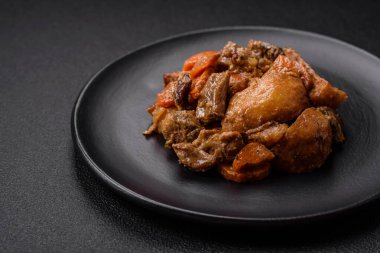 Lezzetli sebze güveci, patates, sığır eti, mantar, havuç, tuz, baharat ve otlar koyu beton arka planda.